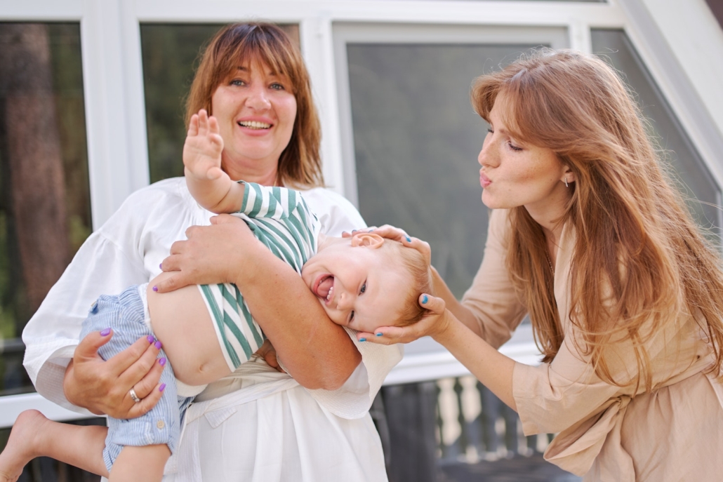 Middle aged female holding pretty little boy and mother patting him on head