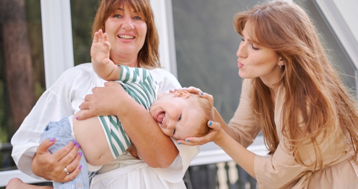 Middle aged female holding pretty little boy and mother patting him on head