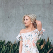 woman in white floral dress standing near gray wall