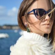 woman wearing blue-framed cat-eye sunglasses with body of water background