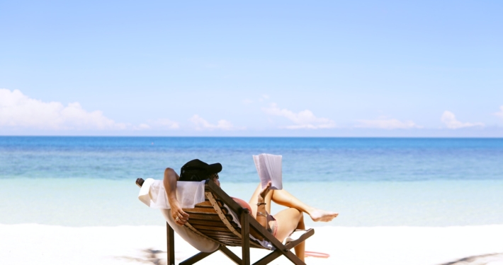 woman sits on brown wooden beach chair