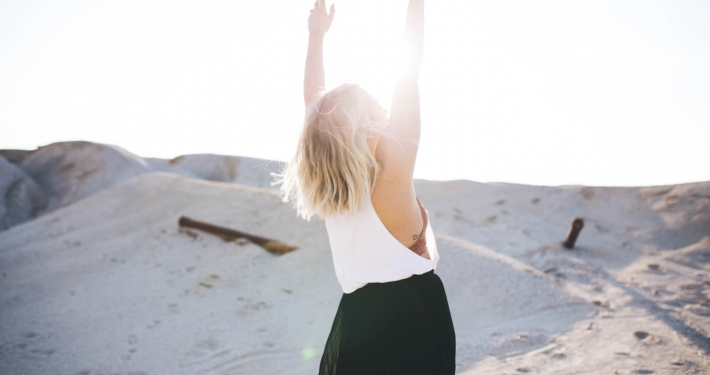 woman standing on the desert while her hands up