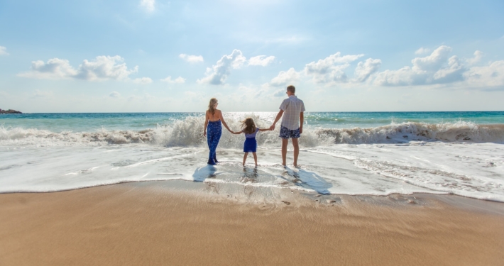 man, woman and child holding hands on seashore