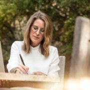 Woman Sitting on Gray Chair While Writing on Table