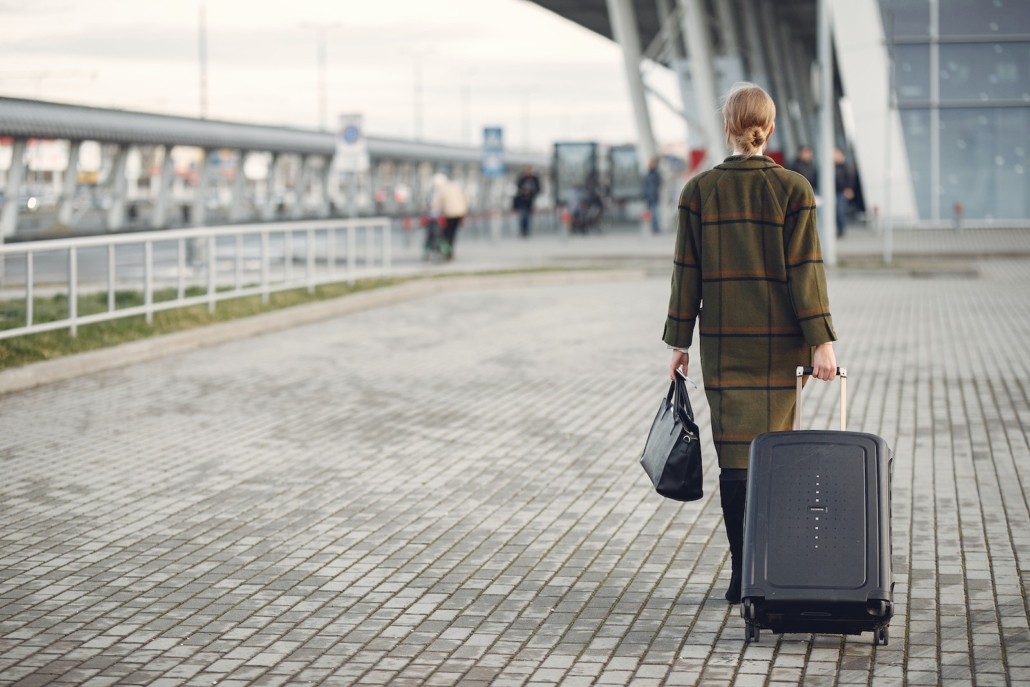 Unrecognizable woman with suitcase walking near airport terminal