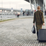 Unrecognizable woman with suitcase walking near airport terminal