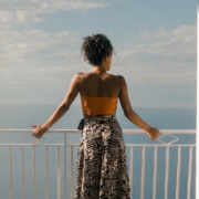 woman wearing orange tube and black skirt facing terrace