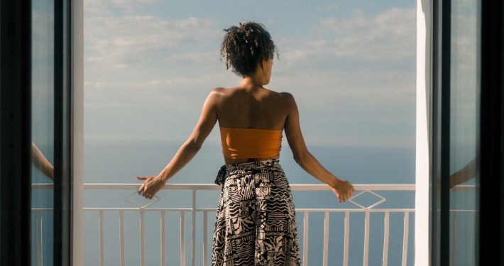 woman wearing orange tube and black skirt facing terrace