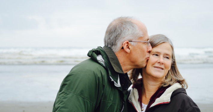 man kissing woman on check beside body of water