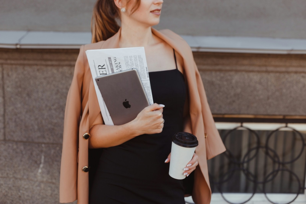 Professional Wardrobe - a woman in a black dress holding a coffee cup and a book - Cosmopolitan Courier