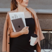 Professional Wardrobe - a woman in a black dress holding a coffee cup and a book - Cosmopolitan Courier