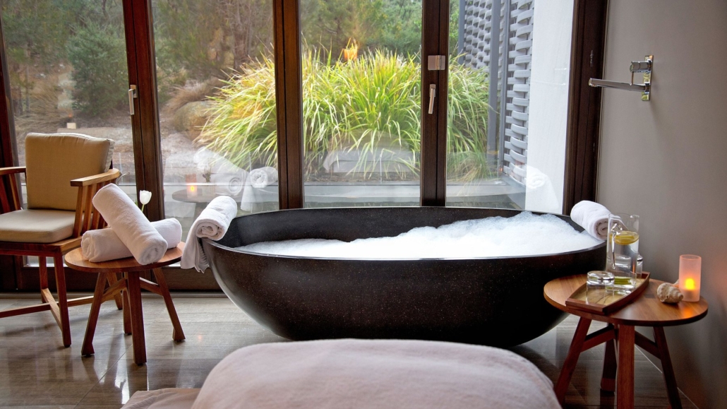 A stone bath in the Saffire spa, set against a window onto native garden.