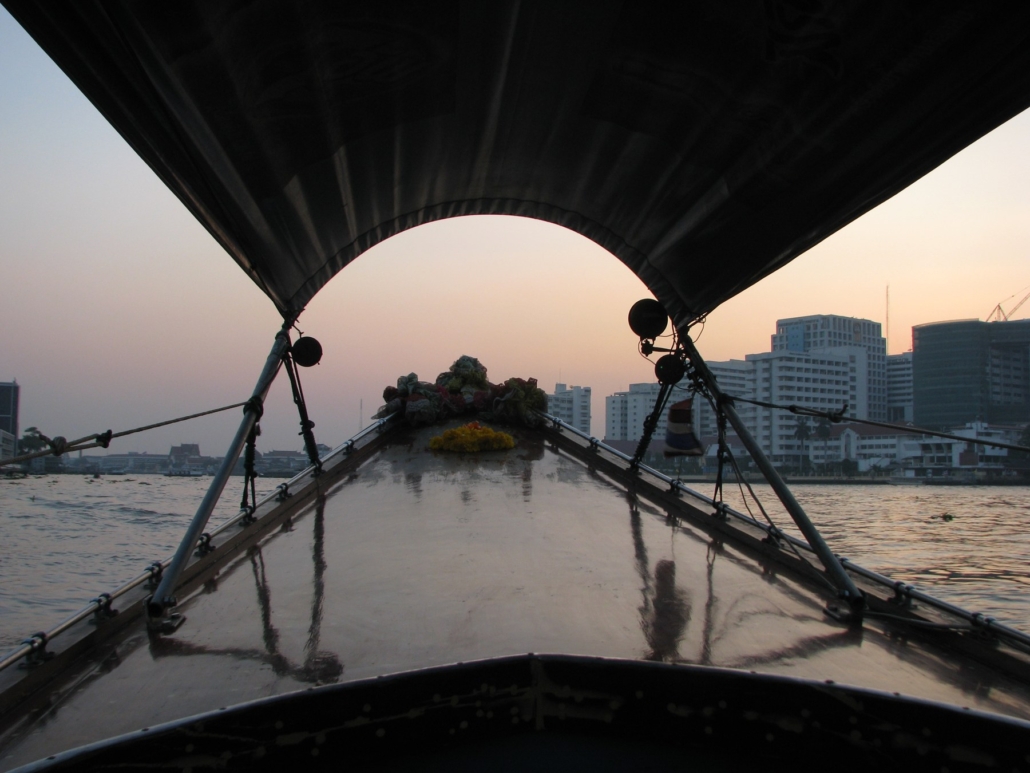 A longtail boat glides through Bangkok’s canals at sunset.